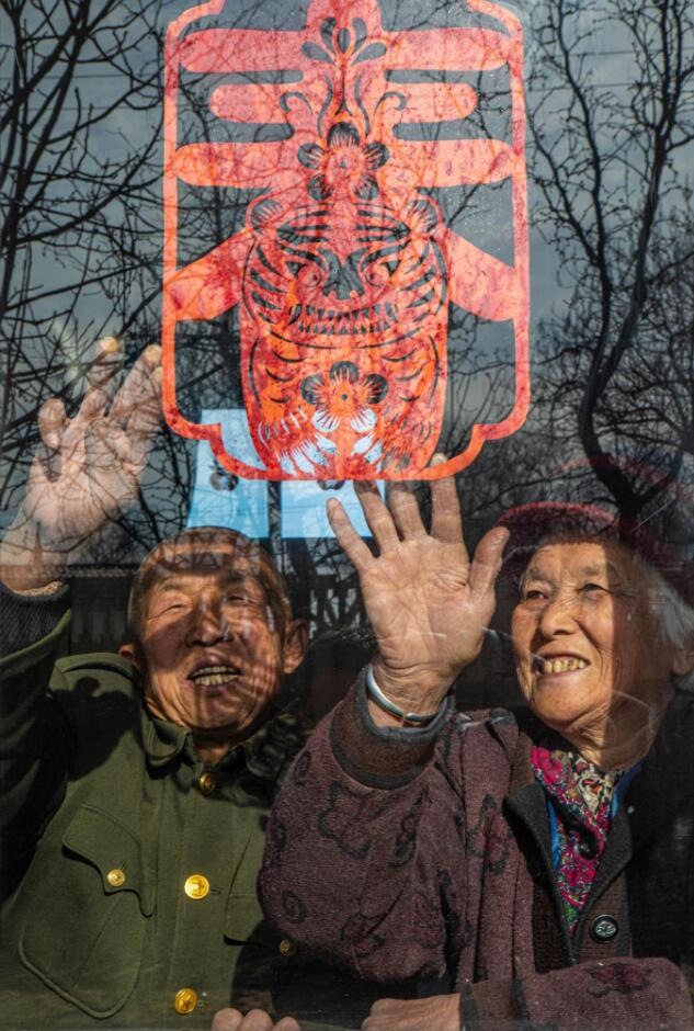 臘月里，霍州市師莊鄉(xiāng)馮南垣村村民師榮光(左)在災后重建的新家里貼窗花。(霍州市委宣傳部供圖)