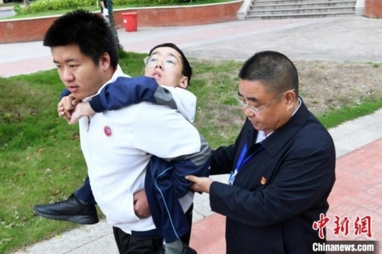 朱金祥背著鐘華強(qiáng)去教室上課的路上，也經(jīng)常碰到值班的校領(lǐng)導(dǎo)和老師前來搭把手。 卓忠偉 攝