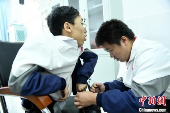 江西省南康中學(xué)北校區(qū)的高三學(xué)生朱金祥(右)正在給鐘華強(qiáng)(左)系好鞋帶。 卓忠偉 攝