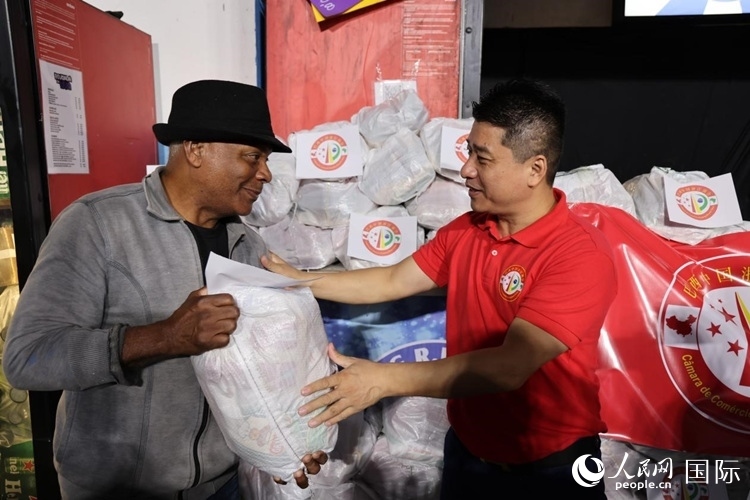 巴西中國(guó)浙江商會(huì)會(huì)長(zhǎng)鄭俠茂向社區(qū)居民轉(zhuǎn)交捐贈(zèng)物資。人民網(wǎng)記者 時(shí)元皓攝