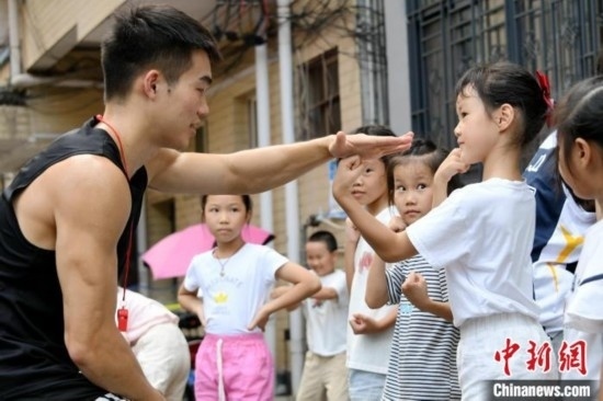 圖為大學生志愿者在組織孩子們參加體育健身活動。廖光福 攝