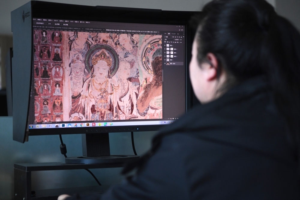敦煌研究院文物數(shù)字化保護團隊圖像處理人員年海麗在拼接壁畫圖像（2023年4月25日攝）。數(shù)字化探索為莫高窟的保護與傳承開辟了全新路徑，數(shù)字技術(shù)讓敦煌文物走出洞窟，跨出國門，走向“永久保存、永續(xù)利用”。新華社記者 陳斌 攝