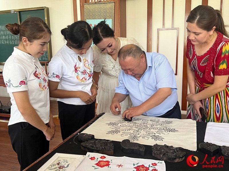 國家級非物質文化遺產(chǎn)模戳印花布技藝傳承人吾吉阿西木?吾舒爾展示模戳印花布的制作過程。人民網(wǎng)記者 常雪梅攝