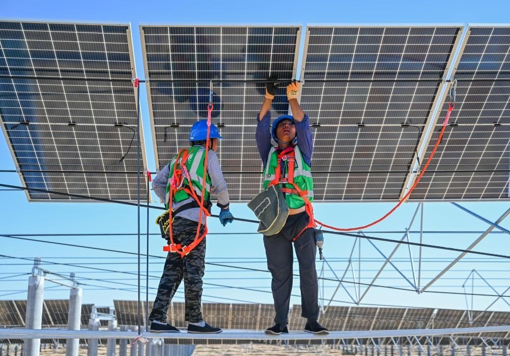 2023年7月22日，工人在位于內(nèi)蒙古杭錦旗庫布其沙漠億利生態(tài)示范區(qū)的蒙西基地庫布其200萬千瓦光伏治沙項目工地安裝光伏板。新華社記者 劉磊 攝