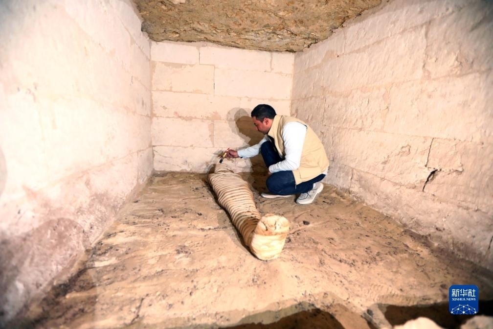 10月15日，在埃及明亞省考古現場，考古人員清理一座石鑿墓中的木乃伊。新華社發(fā)（艾哈邁德·戈馬攝）