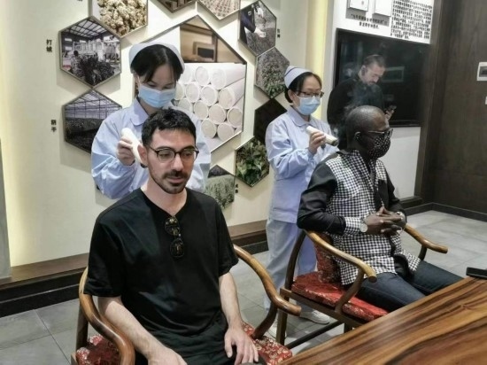 2023“一帶一路”媒體合作論壇聯(lián)合采訪團團員在九牛草展示館體驗艾灸。（本報記者 黃超攝）