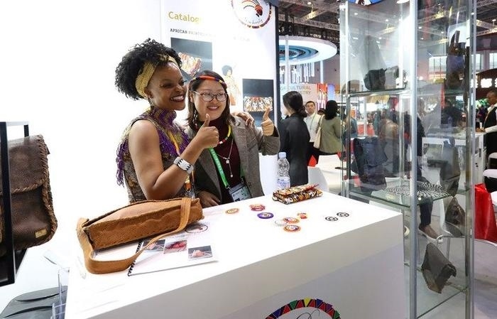 11月6日，一位參觀者（右）在第六屆進(jìn)博會(huì)國家展南非展臺(tái)試戴傳統(tǒng)首飾。