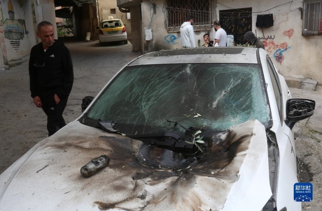 12月17日，在約旦河西岸城市圖勒凱爾姆附近的一處難民營，人們查看在沖突中損毀的車輛。新華社發(fā)（尼達爾·艾仕塔耶攝）