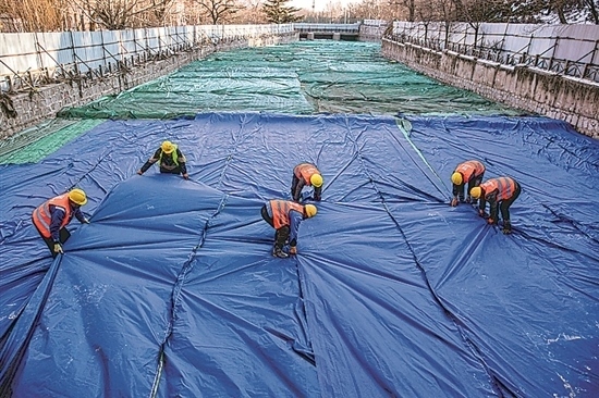 1月3日，房山區(qū)東風(fēng)街道，工人正在修復(fù)的河道內(nèi)給混凝土鋪設(shè)保溫布。