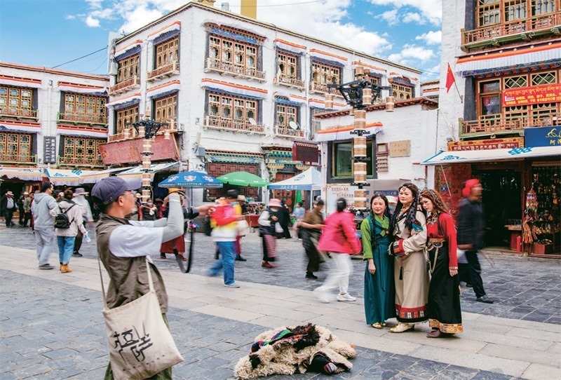 千年八廓街，見(jiàn)證民族團(tuán)結(jié)。2021年7月，習(xí)近平總書(shū)記來(lái)到位于西藏拉薩老城區(qū)的八廓街，感慨地說(shuō)：“千年八廓街，是我們各民族建起來(lái)的八廓街。各民族文化在這里交流交往交融，我們中華民族的大家庭在這里其樂(lè)融融?！眻D為2023年6月13日，游客身著藏裝在八廓街拍照留念。 新華社記者 姜帆/攝