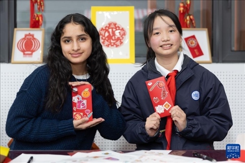 1月28日，美國(guó)馬斯卡廷中學(xué)學(xué)生（左）和復(fù)旦大學(xué)第二附屬學(xué)校學(xué)生展示互相送出的寫(xiě)有寄語(yǔ)祝福的紅包。 新華社記者 王翔 攝