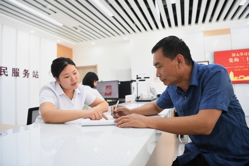2023年5月23日，河北雄安新區(qū)容東片區(qū)南文營社區(qū)居民（右）在社區(qū)便民服務(wù)站辦理業(yè)務(wù)。