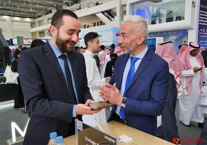 兩名觀眾在榮耀手機展臺前交流。人民網(wǎng)記者 管克江攝