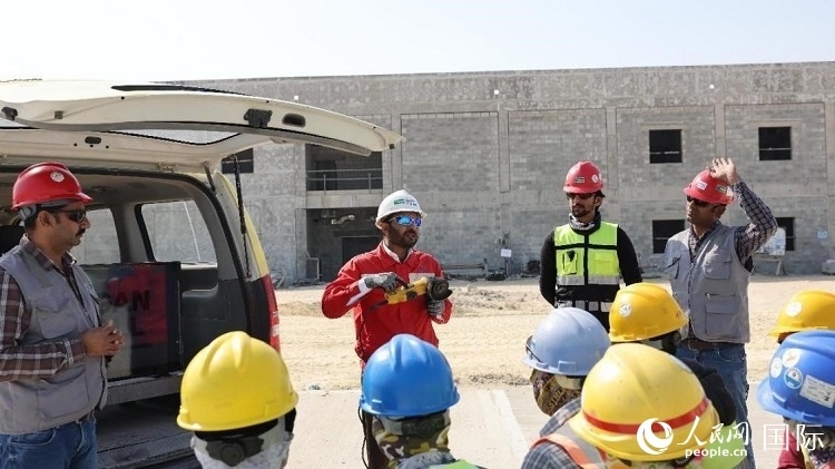 穆薩瓦爾(圖中紅衣人）現(xiàn)場演示工具操作規(guī)范。人民網(wǎng)記者 管克江攝