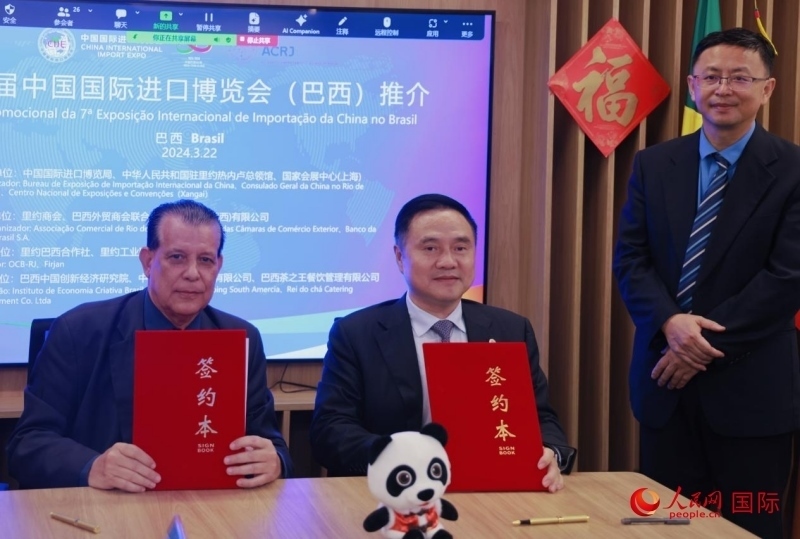 巴西外貿(mào)商會聯(lián)合會會長阿代爾·羅伯托（左）與中國國際進口博覽局副局長吳政平（中）現(xiàn)場簽訂協(xié)議。人民網(wǎng)記者 宋亦然攝