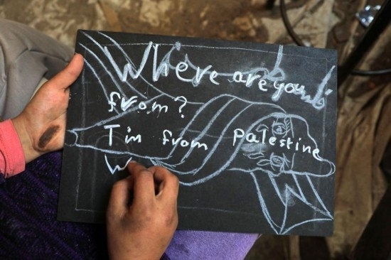 2023年12月28日，一名學(xué)生在加沙地帶南部城市拉法一所學(xué)校的臨時(shí)教室中寫下“我來自巴勒斯坦”的字樣。新華社發(fā)（里澤克·阿卜杜勒賈瓦德攝）