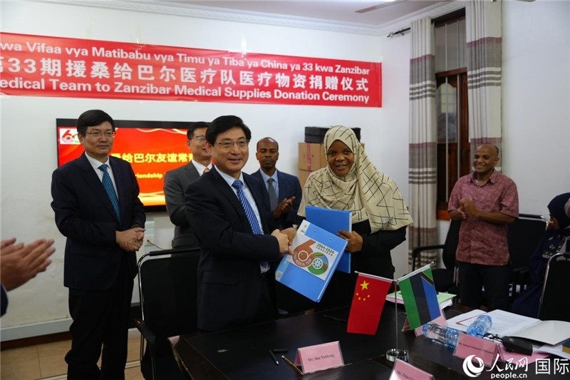 江蘇省蘇北人民醫(yī)院黨委書記束余聲與桑衛(wèi)生部首席秘書哈比巴交換捐贈書。中國援桑醫(yī)療隊供圖