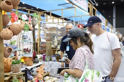 游客在蘭納博覽會特色展位上選購工藝品。人民網(wǎng)記者楊一攝