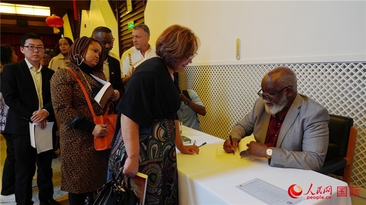 譚哲理在活動(dòng)現(xiàn)場(chǎng)簽名贈(zèng)書。人民網(wǎng) 劉暢攝