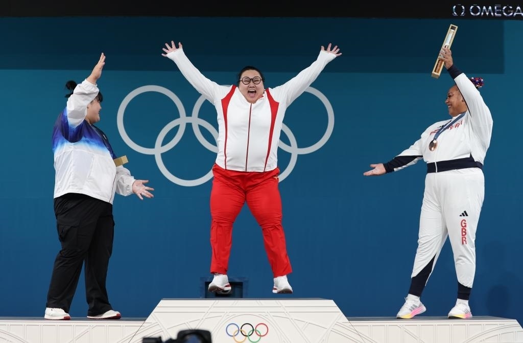中國選手李雯雯（中）在巴黎奧運會舉重女子81公斤以上級頒獎儀式中登上領(lǐng)獎臺（2024年8月11日攝）。新華社記者 楊磊 攝
