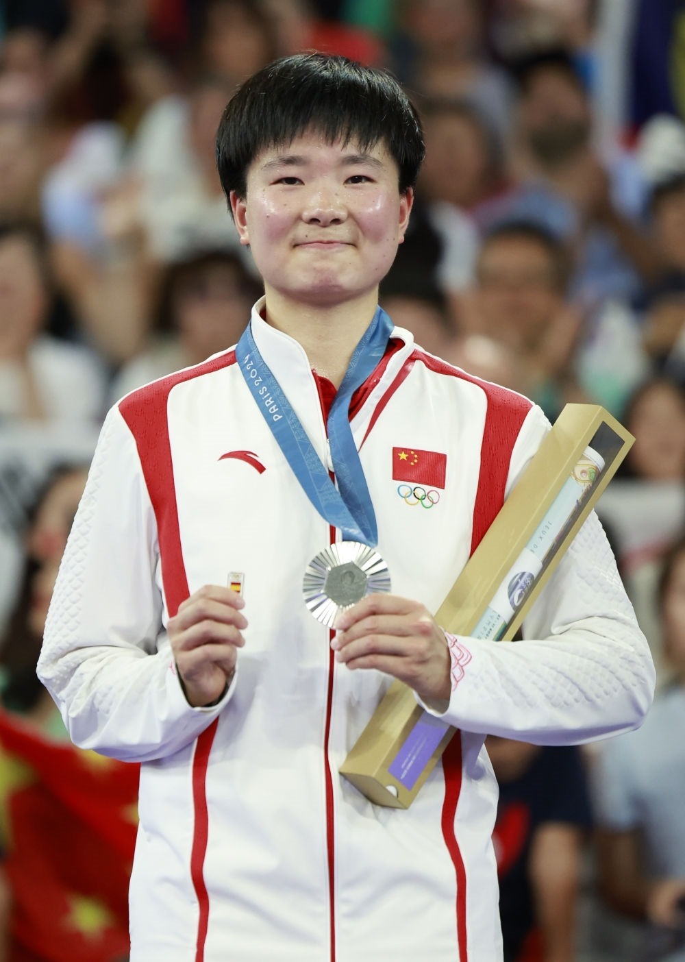巴黎奧運會羽毛球女子單打亞軍、中國選手何冰嬌在頒獎儀式上一手握著銀牌，一手握著西班牙奧委會徽章（2024年8月5日攝）。新華社記者 任正來 攝