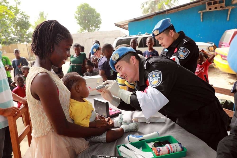 2017年12月28日，在利比里亞蒙羅維亞，中國維和警察防暴隊醫(yī)療人員為兒童做口腔檢查。