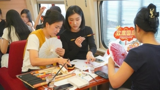 10月1日，旅客們在G1634次列車上給油紙傘作畫。新華社記者周義 攝