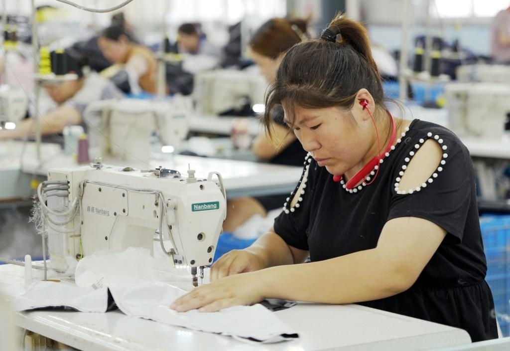 5月20日，村民在李寨村服裝加工廠內(nèi)忙碌。河南省周口市沈丘縣馮營鎮(zhèn)李寨村地處豫東平原。近年來，乘著脫貧攻堅與鄉(xiāng)村振興政策的東風(fēng)，李寨村積極探索產(chǎn)業(yè)發(fā)展模式，通過“龍頭企業(yè)+村集體經(jīng)濟+農(nóng)戶”的方式，逐漸發(fā)展形成肉牛養(yǎng)殖、設(shè)施農(nóng)業(yè)、服裝加工、康養(yǎng)民宿等產(chǎn)業(yè)，以產(chǎn)業(yè)振興助力鄉(xiāng)村振興。新華社記者 李嘉南 攝