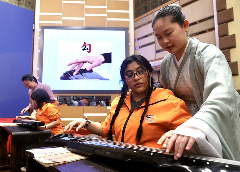 2024年3月20日，美國華盛頓州中學(xué)生代表團(tuán)北京大學(xué)交流活動在北京大學(xué)英杰交流中心舉行。圖為來自華盛頓州的中學(xué)生體驗(yàn)古琴。