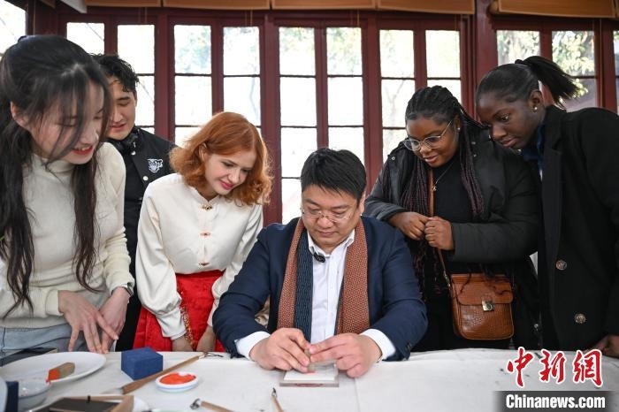 1月20日，篆刻家王臻向外籍留學(xué)生展示篆刻印章。當(dāng)日，來自巴西、馬來西亞、加納、哈薩克斯坦的外籍留學(xué)生在浙江杭州西泠印社體驗福貼、春聯(lián)和篆刻，感受古老的中國傳統(tǒng)文化。中新社記者 王剛 攝