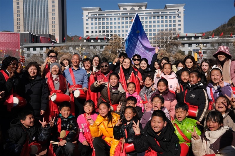 中外青年學(xué)子在安塞文化廣場(chǎng)觀看陜北腰鼓和大秧歌表演后合影留念，大家踏著鼓點(diǎn)共舞，翻飛的紅綢與躍動(dòng)的身影交織，在黃土地廣場(chǎng)上繪出一幅生動(dòng)的陜北民俗互動(dòng)畫(huà)卷