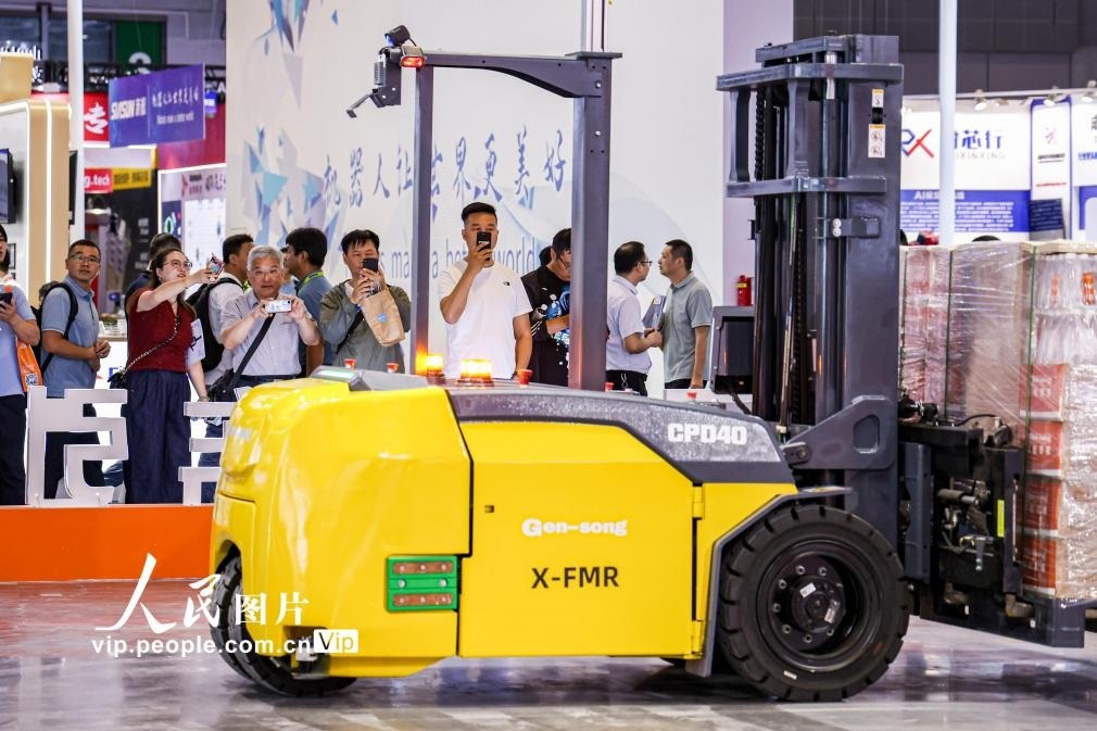 第24屆中國工博會現(xiàn)場，觀眾觀看叉取機(jī)器人作業(yè)演示。王初攝（人民圖片網(wǎng)）