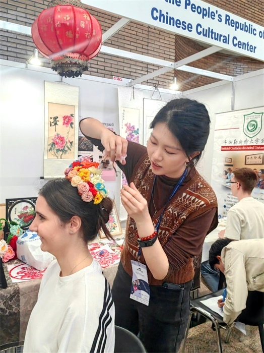 展覽正值羅馬尼亞迎春花節(jié)，國際中文教師志愿者潘婧穎向游客們介紹了國家非物質(zhì)文化遺產(chǎn)——福建泉州的簪花文化。布加勒斯特大學(xué)孔子學(xué)院供圖。