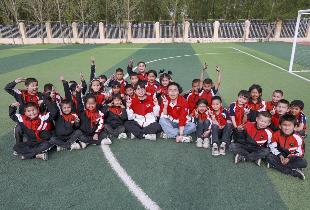 4月23日，在新疆克州阿圖什市哈拉峻鄉(xiāng)謝依特小學(xué)，支教教師王俊文（中左）、李軻凡（中右）和學(xué)生在一起。