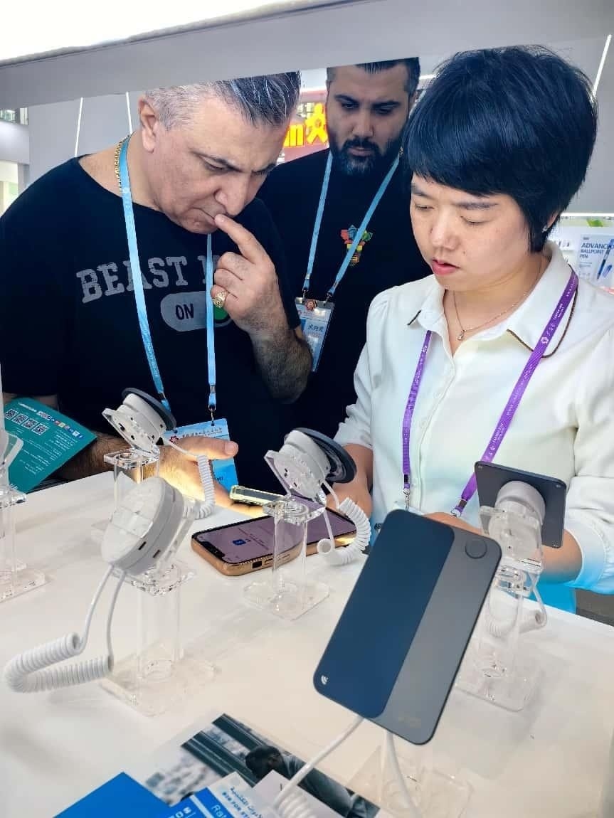 展臺工作人員向外商展示“AI TOP翻譯終端”。圖片來源：受訪者提供
